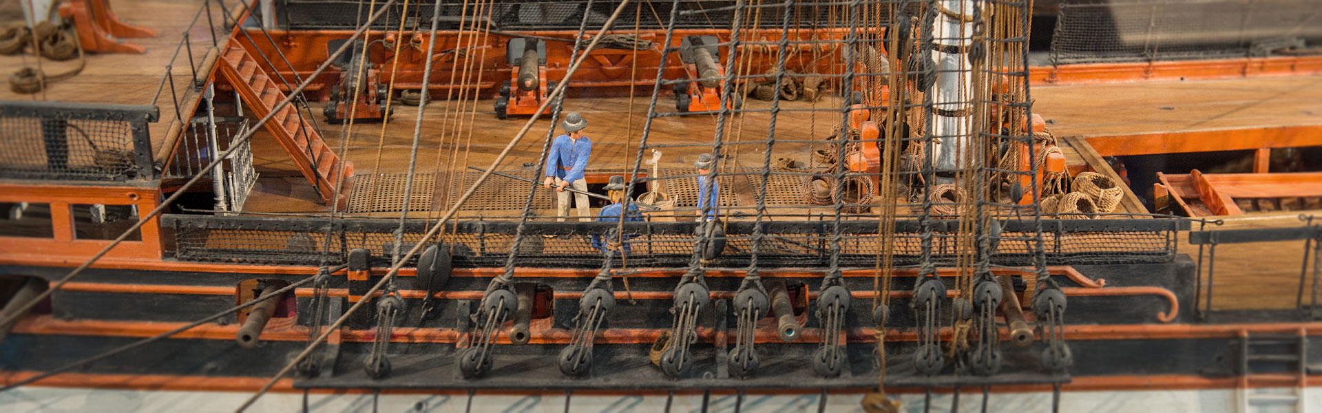 Närbild av Originalmodellen. Tre miniatyrfigurer på däck. I förgrunden detaljer av riggen. I bakgrunden miniatyr kanoner.