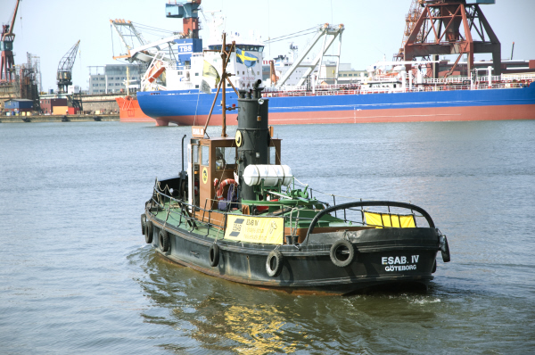 Esab fyra är en bogserbåt med svart skrov och bildäck som fendrar. Han har ett öppet grönt däck med brunmålad styrhytt i fören. Midskepps har han en stor svart skorsten. Fartyget är avbildat under gång akterifrån i en hamnmiljö i Göteborg. 