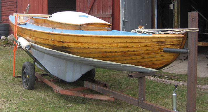 Anden är en liten segelbåt med klinkat furuskrov och blåmålat däck. Hon ligger i en vagga på torra land.