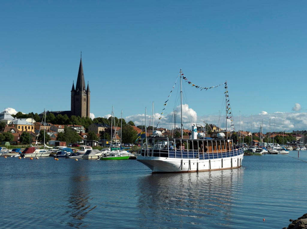 Marianne är ett mindre passagerarfartyg med vitt skrov, blått kapell innanför mantåget och ett enklare tak som solskydd. I fören syns en hytt och en mindre salong i brunt trä. Mellan de två masterna vajar ett flaggspel. På bilden går fartyget in i Mariestads hamn och i bakgrunden syns domkyrkan. 