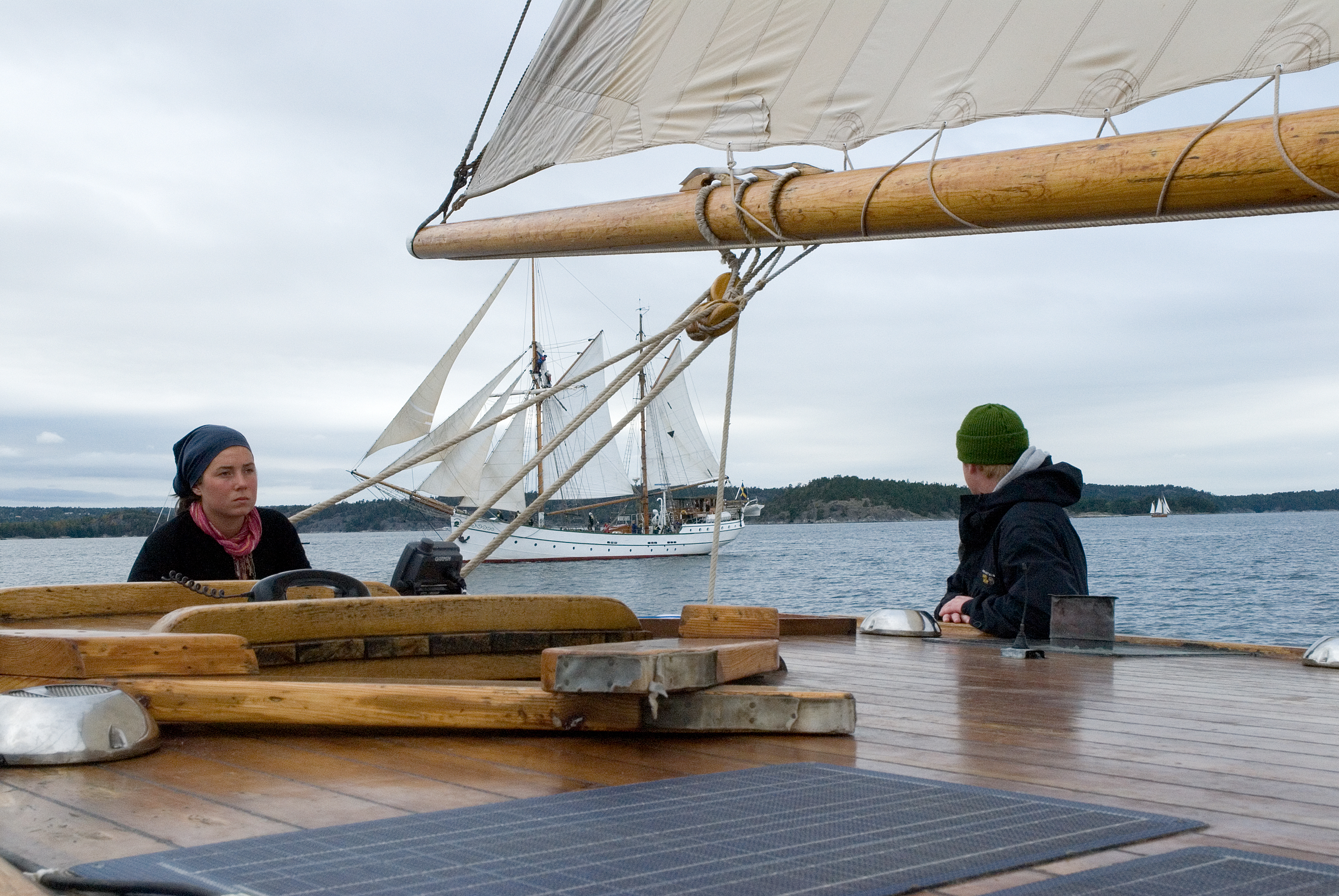 Två tonåriga elever står på ett segelfartyg. Bakom fartyget seglar en tvåmastad skonare.